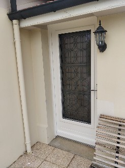 Pose de porte d'entrée en bois avec grille en fer forgé