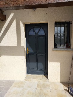 Pose d'une porte d'entrée en bois exotique gris extérieur et blanc intérieur.
